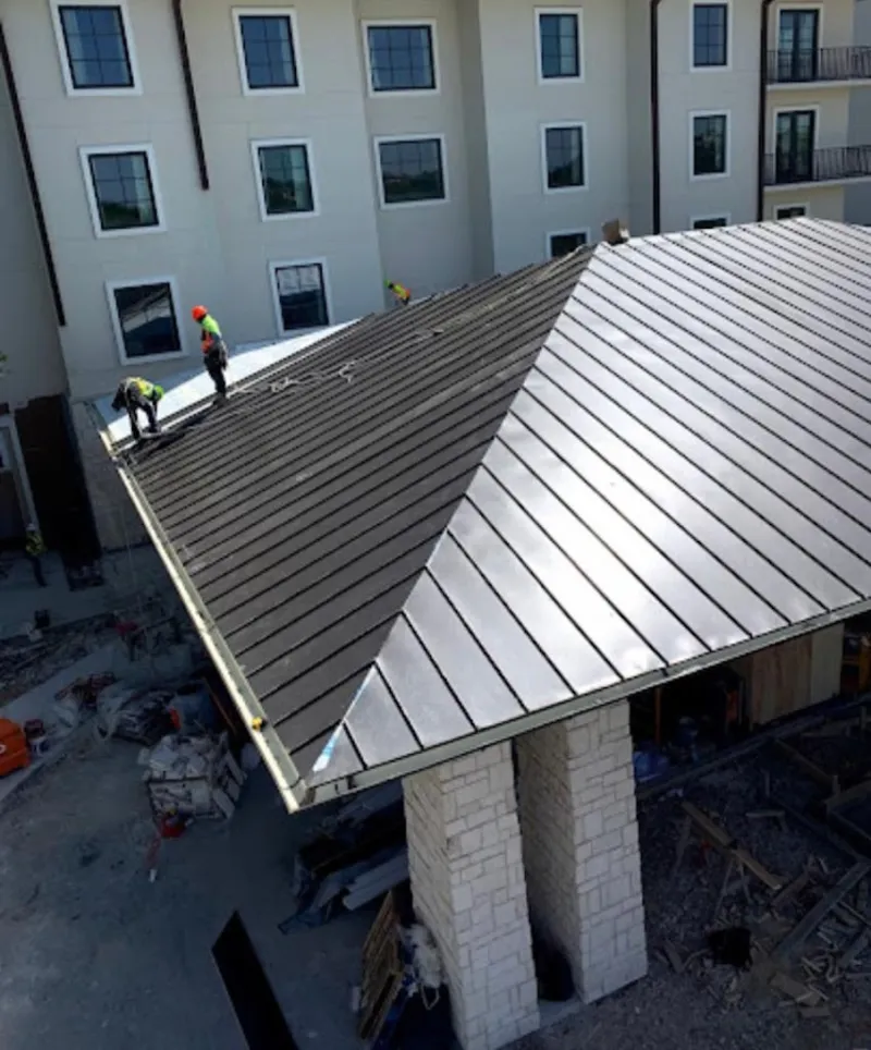 Crew installing standing seam metal roof panels on a commercial project in Corry